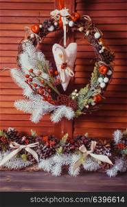 Christmas wreath on the wooden wall. Red and white elements, textile heart hangs. Red and white Christmas wreath
