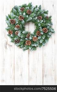 Christmas wreath with cones on rustic wooden background. Christmas decoration