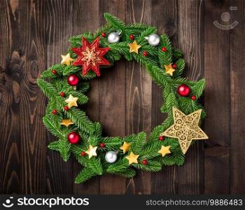 Christmas wreath with decor, Top view of tree fir spruce branches is rolled in a circle and ornament star on black table wood background, New year festive decoration concept