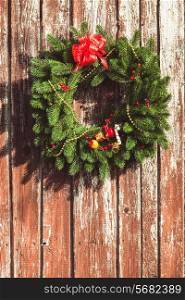 Christmas wreath with decorations on the shabby wooden door.