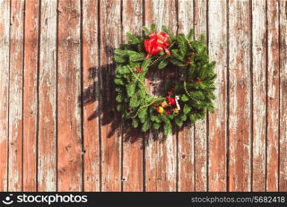 Christmas wreath with decorations on the shabby wooden door.
