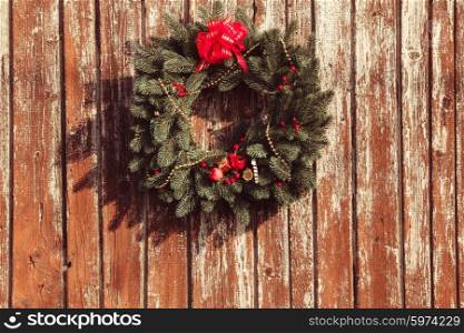 Christmas wreath with decorations on the shabby wooden door.. The Christmas wreath