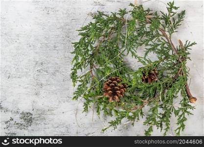 Christmas wreath with green branches, pine cones and natural festive decorations. Rustic christmas wreath hanging on the wall. Seasonal holiday advent