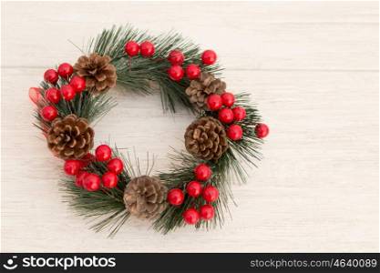 Christmas wreath with pine cones and red berries on a grey background