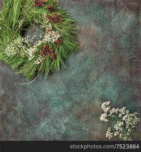 Christmas wreath with pine cones and white flowers on concrete stone background. Vintage style tonned picture