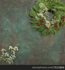 Christmas wreath with pine cones and white flowers on stone background. Festive arrangement
