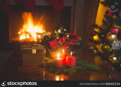 Christmas wreath with red candles in living room with burning fireplace