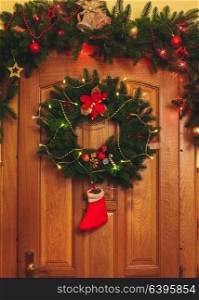 Christmas wreath with red sock and border on the door. Christmas wreath on door