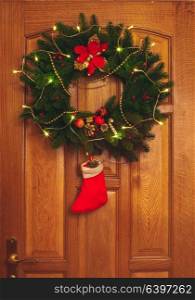 Christmas wreath with red sock on the door. Christmas wreath on door