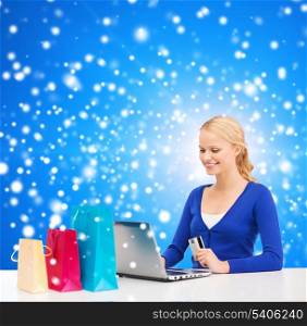 christmas, x-mas and online shopping concept - smiling woman with shopping bags, laptop and credit card