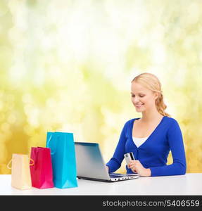 christmas, x-mas and online shopping concept - smiling woman with shopping bags, laptop and credit card