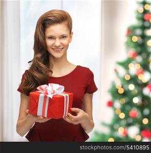 christmas, x-mas, celebration concept - smiling woman in red dress with gift box