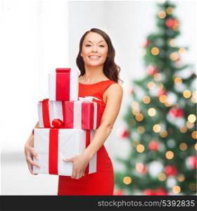 christmas, x-mas, celebration concept - smiling woman in red dress with many gift boxes