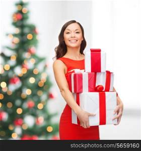 christmas, x-mas, celebration concept - smiling woman in red dress with many gift boxes