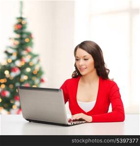 christmas, x-mas, electronics, gadget concept - smiling woman in red clothes with laptop computer