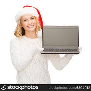 christmas, x-mas, electronics, gadget concept - smiling woman in santa helper hat with blank screen laptop computer