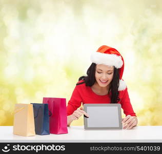 christmas, x-mas, electronics, gadget concept - smiling woman in santa helper hat with blank screen tablet pc and shopping bags