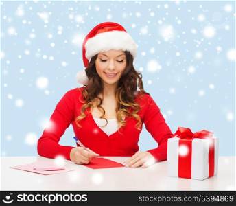christmas, x-mas, gifts, presents, celebration concept - smiling woman in santa helper hat with gift box and postcard