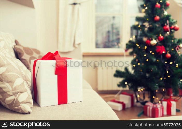christmas, x-mas, holidays, winter and happiness concept - gift box on coach at home
