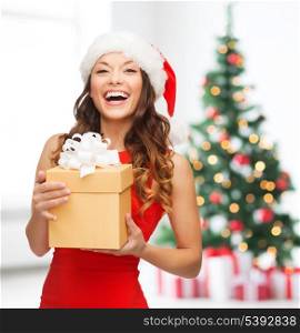 christmas, x-mas, new year, winter, happiness concept - smiling woman in santa helper hat with gift box