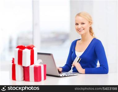 christmas, x-mas, online shopping concept - smiling woman with gift boxes, laptop computer and credit card