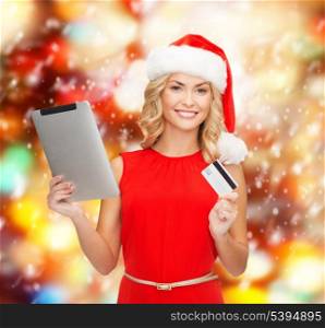 christmas, x-mas, online shopping concept - woman in santa helper hat with tablet pc computer and credit card