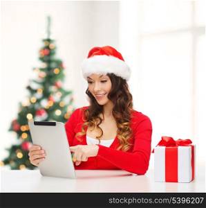 christmas, x-mas, online shopping concept - woman in santa helper hat with gift box and tablet pc computer