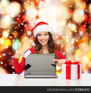 christmas, x-mas, online shopping concept - woman in santa helper hat with gift box, laptop computer and credit card