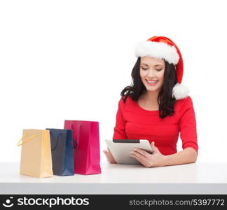 christmas, x-mas, online shopping concept - woman in santa helper hat with gift box and tablet pc computer