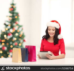 christmas, x-mas, online shopping concept - woman in santa helper hat with gift box and tablet pc computer