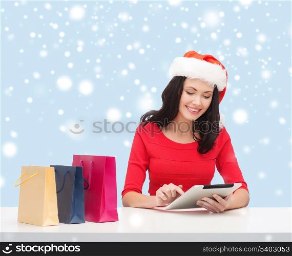 christmas, x-mas, online shopping concept - woman in santa helper hat with gift box and tablet pc computer
