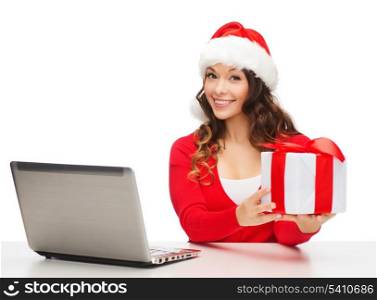 christmas, x-mas, online shopping concept - woman in santa helper hat with gift box and laptop computer