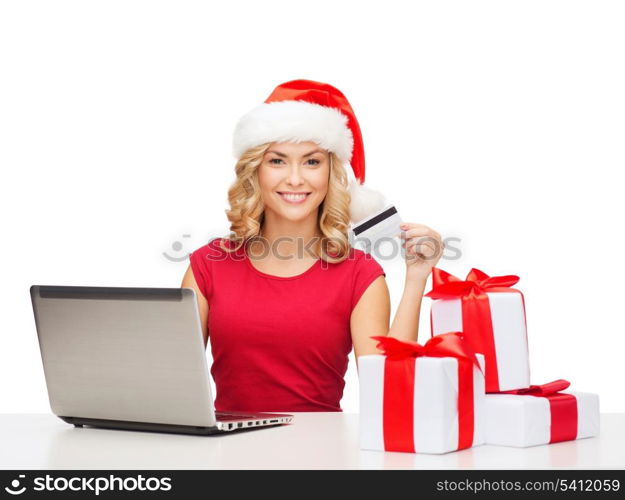 christmas, x-mas, online shopping concept - woman in santa helper hat with gift boxes, laptop computer and credit card