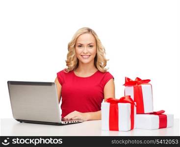 christmas, x-mas, online shopping concept - woman with gift boxes and laptop computer