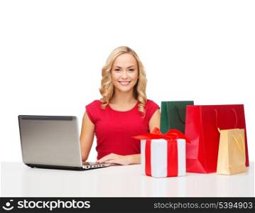 christmas, x-mas, online shopping concept - woman with gift boxes, bags and laptop computer