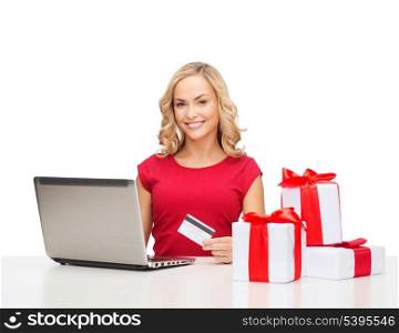 christmas, x-mas, online shopping concept - woman with gift boxes, laptop computer and credit card