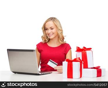 christmas, x-mas, online shopping concept - woman with gift boxes, laptop computer and credit card