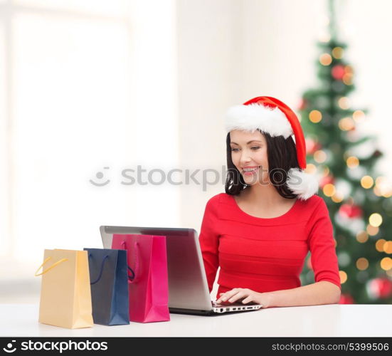 christmas, x-mas, online shopping concept - woman with shopping bags and laptop computer