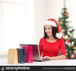 christmas, x-mas, online shopping concept - woman with shopping bags and laptop computer