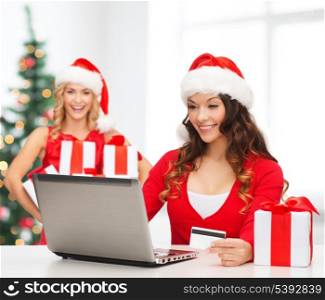 christmas, x-mas, online shopping concept - women in santa helper hat with gift box, laptop computer and credit card