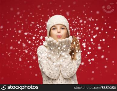 christmas, x-mas, people, happiness concept - happy girl in winter clothes blowing on palms