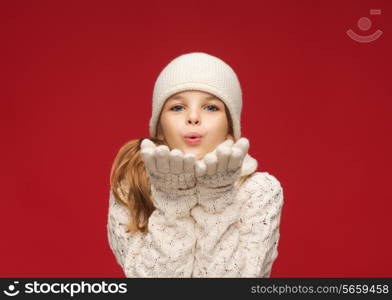 christmas, x-mas, people, happiness concept - happy girl in winter clothes blowing on palms