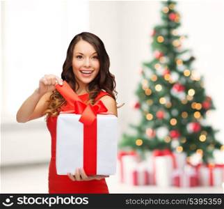 christmas, x-mas, valentine&#39;s day, celebration concept - smiling woman in red dress with gift box