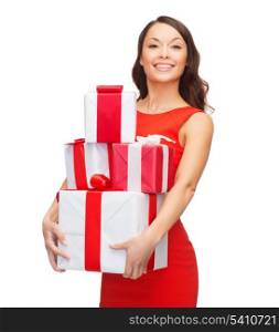 christmas, x-mas, valentine&#39;s day, celebration concept - smiling woman in red dress with many gift boxes