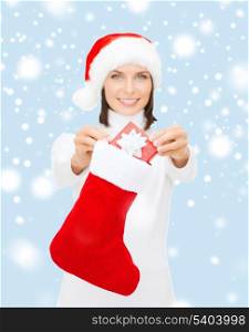 christmas, x-mas, winter and happiness concept - smiling woman in santa helper hat with small gift box and stocking