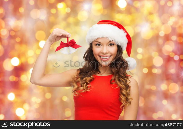 christmas, x-mas, winter and people concept - smiling woman in santa helper hat with jingle bells over holidays lights background