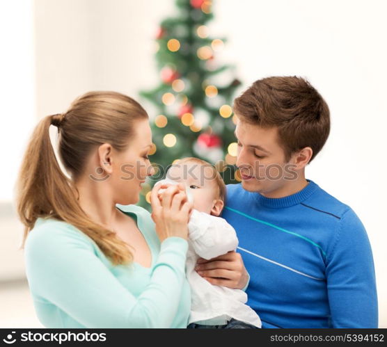 christmas, x-mas, winter, family, people, happiness concept - happy family and adorable baby with feeding-bottle