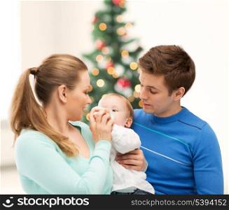 christmas, x-mas, winter, family, people, happiness concept - happy family and adorable baby with feeding-bottle