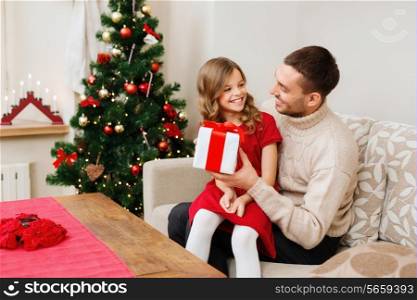 christmas, x-mas, winter, happiness and people concept - smiling father and daughter holding gift box and looking at each other