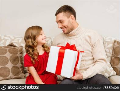 christmas, x-mas, winter, happiness and people concept - smiling father and daughter holding gift box and looking at each other